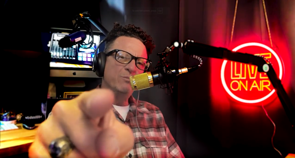 Timithee Huggins pointing at the screen with a 'Live On Air' sign behind him